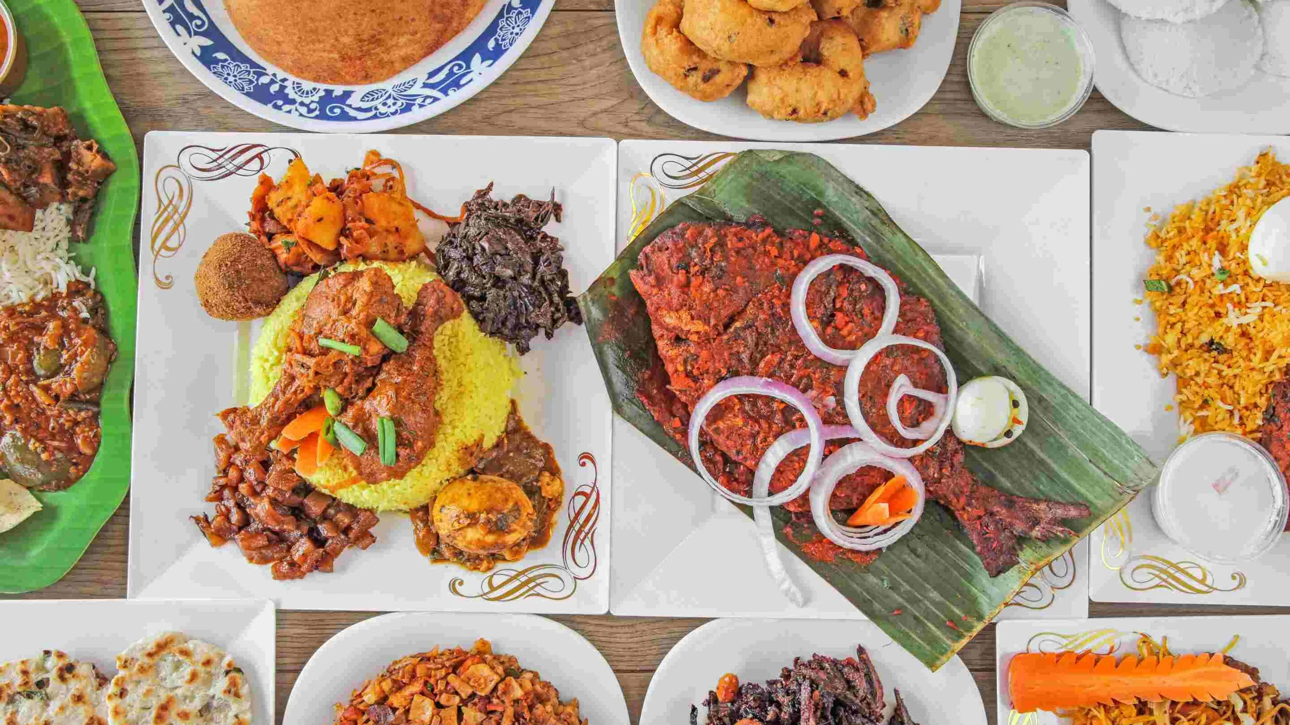 Table of Sri Lankan dishes: masala-grilled pomfret on banana leaf, yellow rice with chicken curry, biryani with egg, kothu roti, vadai and idli