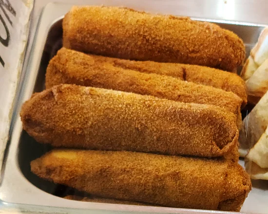 Crumb-fried mutton rolls stacked in a counter tray