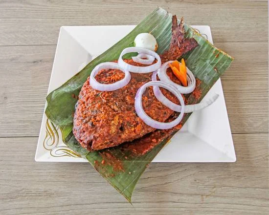 Whole pomfret grilled in red masala on banana leaf with onion rings
